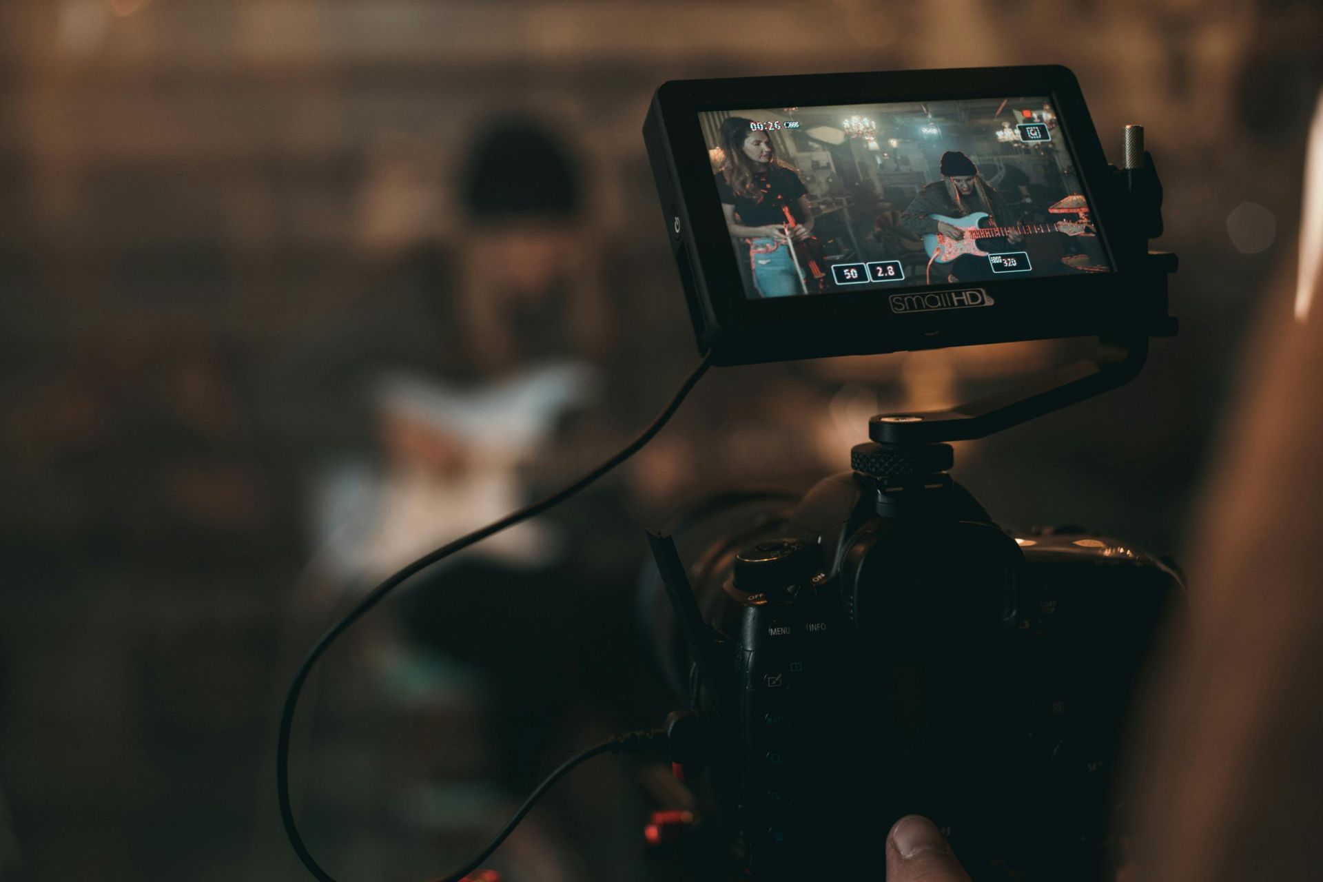 A cinematic close-up of filming a rock band performance with focus on camera screen.