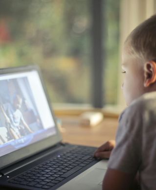 A young boy engrossed in watching content on a laptop in a cozy home setting.